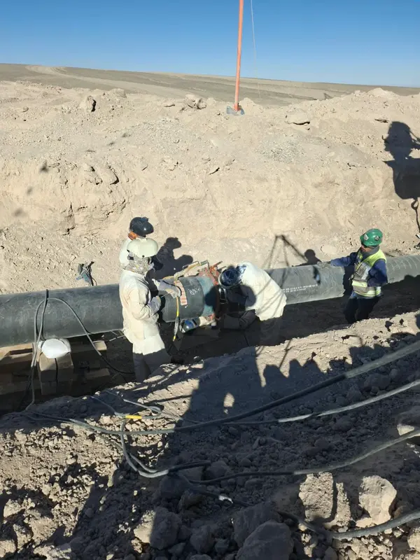 Soldadores trabajando sobre la línea de tubería en terreno